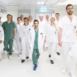 Menn og kvinner ansatt ved sykehuset gående i uniform u sykehuskorridor.