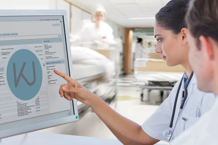 Helsepersonell studerer opplysninger på en dataskjerm inne på sykehuset.