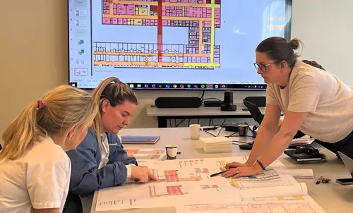 En gruppe kvinner som sitter ved et bord og ser på en skjerm