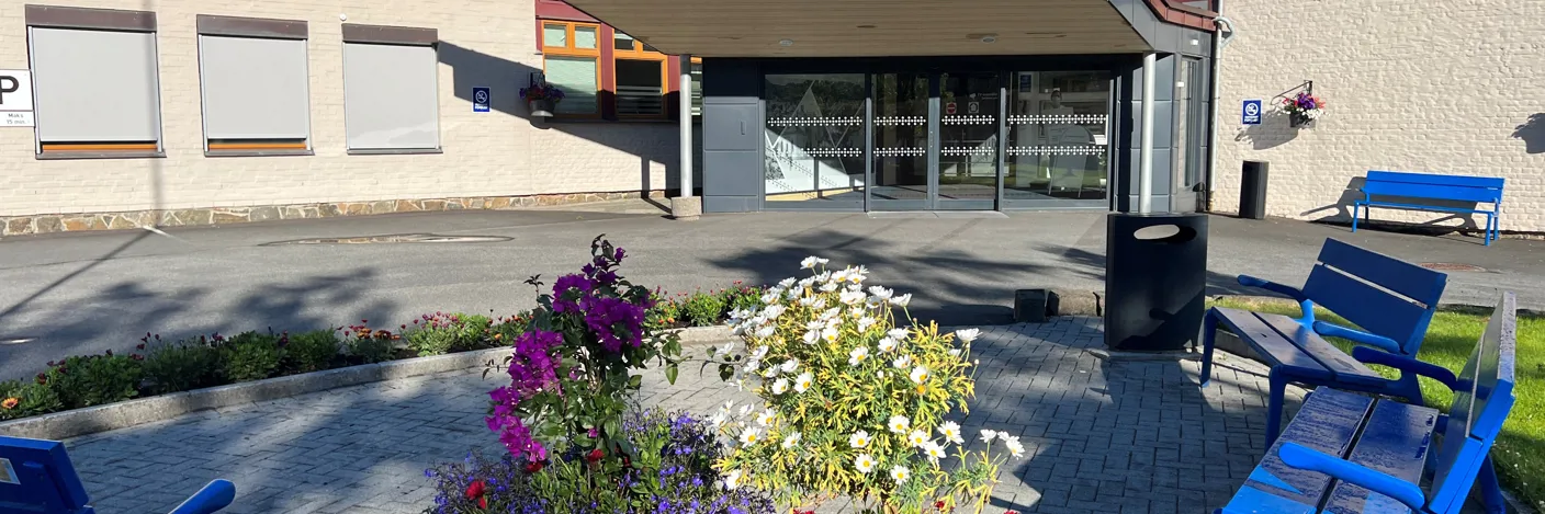 Hovedinngang til Flekkefjord sykehus med uteplass med stoler og blomster