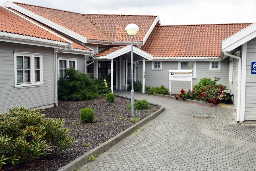 En innkjørsel med et hus og et skilt på den