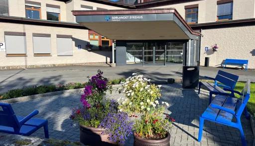 Hovedinngang til Flekkefjord sykehus med uteplass med stoler og blomster